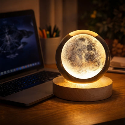 Moon lamp on a desk next to a laptop